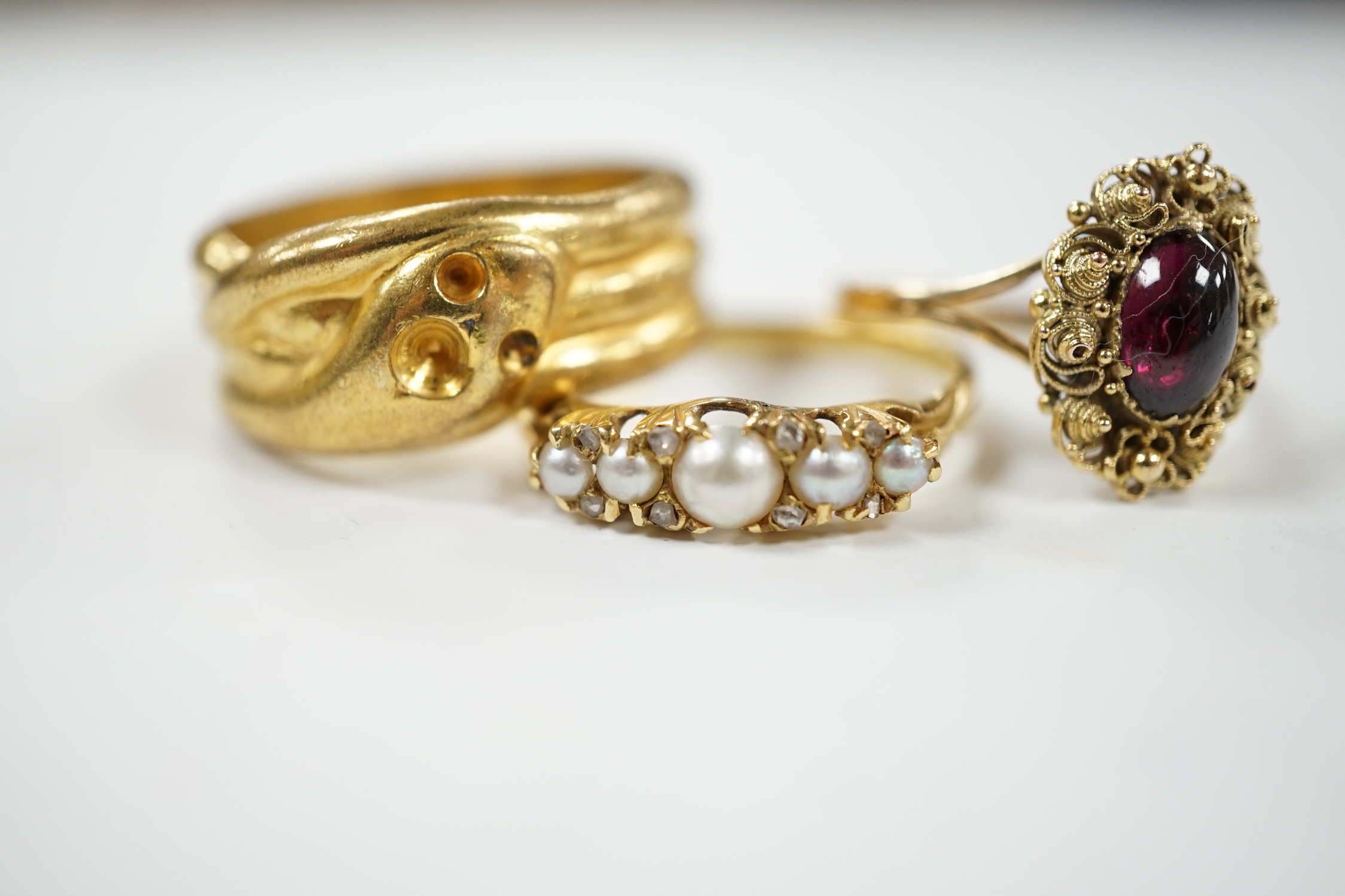 A yellow metal and cabochon garnet set ring, an Edwardian 18ct and graduated split pearl set half hoop ring, with diamond chip spacers and one other ring.